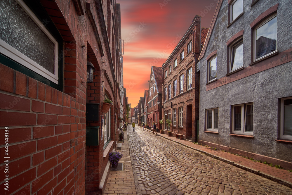 Narrow street in a northern German old town with brick houses under a red evening sky, edited photo