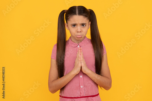 Εκτύπωση καμβά Unhappy girl prayer plead holding palms together in prayer gesture yellow backgr