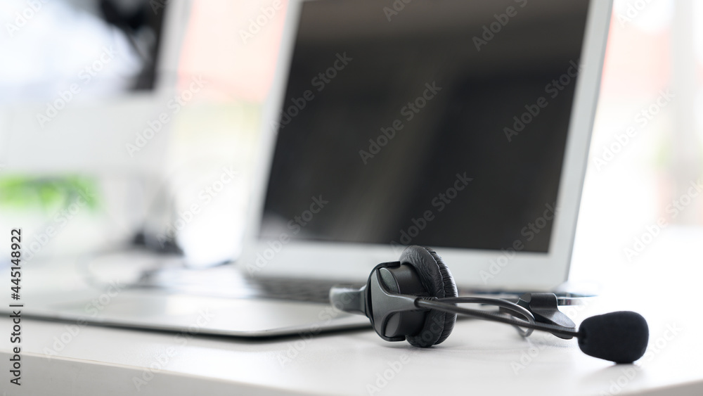 Headsets for call center teams are placed at a desk with a computer and laptop. while the team is in the break