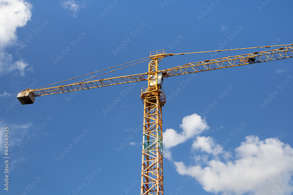 Yellow construction crane at the construction site on a beautiful sky background Yellow construction crane at the construction site on a beautiful sky background