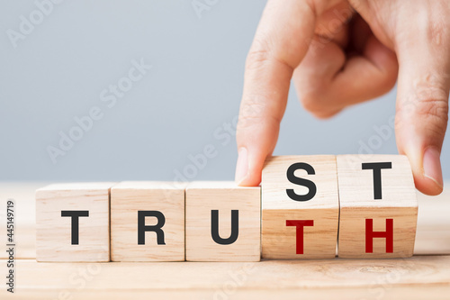 Business man hand change wooden cube block with TRUST and TRUTH business word on table background. Trustworthy, faith, beliefs and honesty concept photo