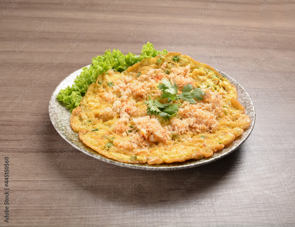 golden stir fried egg omelette with seafood and meat on wood table asian Thai appetiser halal menu