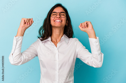 Young caucasian woman isolated on blue background celebrating a victory, passion and enthusiasm, happy expression.