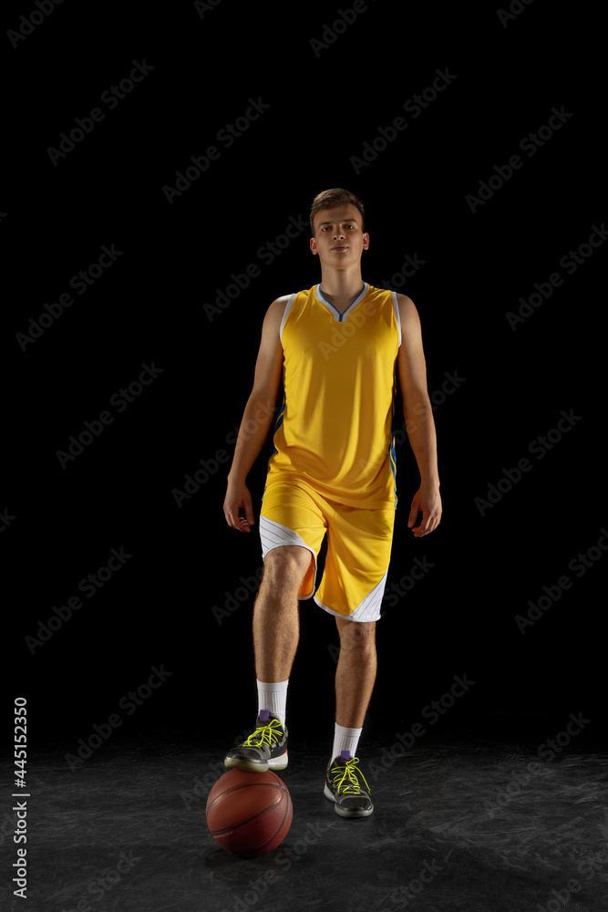 Portrait of young man, basketball player with a ball isolated on dark black studio background. Advertising concept. Fit Caucasian athlete practicing with ball. Portrait of young man, basketball player with a ball isolated on dark black studio background. Advertising concept. Fit Caucasian athlete practicing with ball.