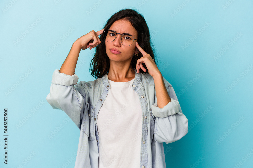 Young caucasian woman isolated on blue background focused on a task, keeping forefingers pointing head. Young caucasian woman isolated on blue background focused on a task, keeping forefingers pointing head.