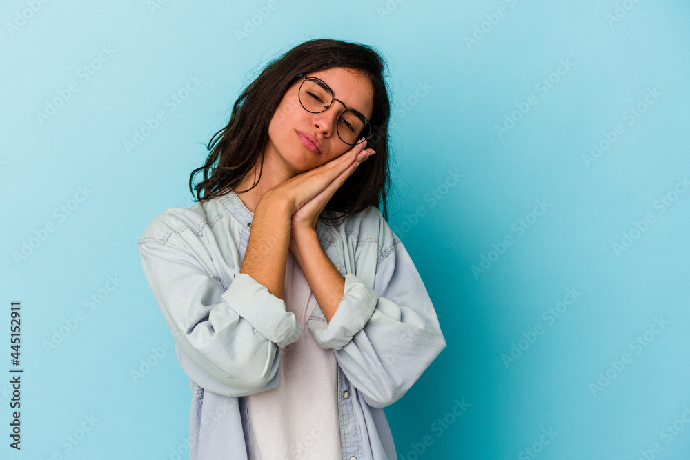 Young caucasian woman isolated on blue background yawning showing a tired gesture covering mouth with hand. Young caucasian woman isolated on blue background yawning showing a tired gesture covering mouth with hand.