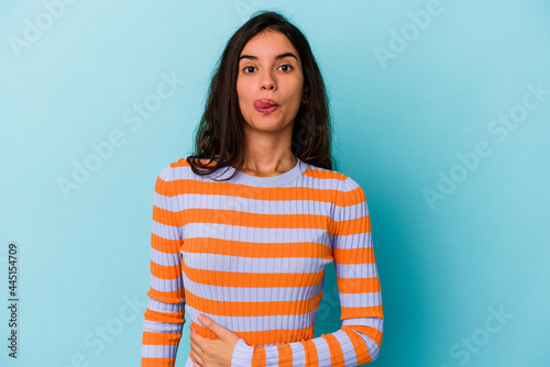 Young caucasian woman isolated on blue background touches tummy, smiles gently, eating and satisfaction concept.