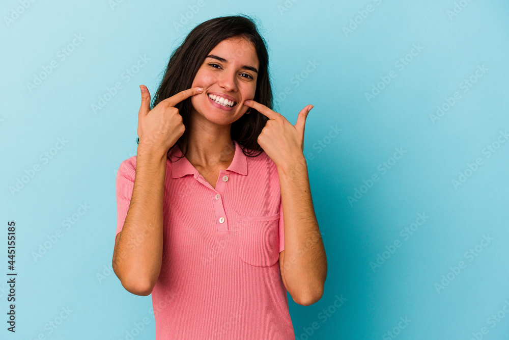 Young caucasian woman isolated on blue background smiles, pointing fingers at mouth. Young caucasian woman isolated on blue background smiles, pointing fingers at mouth.