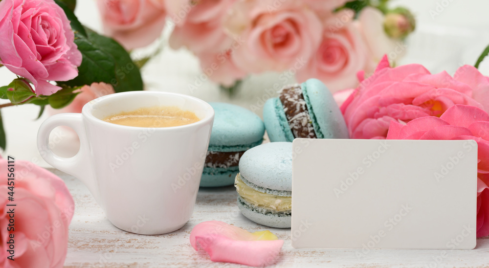 blank white business card and cup with espresso coffee and white ceramic cup with coffee and blue macaron on a white table,