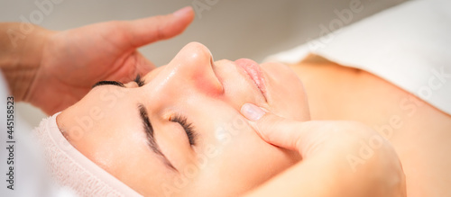 Beautician making lymphatic drainage face massage or facelifting massage at the beauty salon