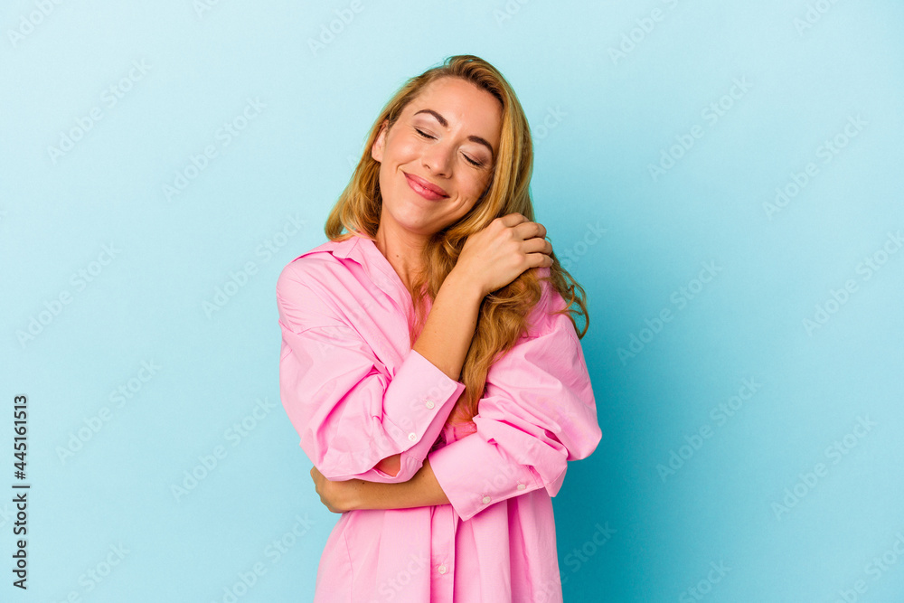 Caucasian woman isolated on blue background hugs, smiling carefree and happy. Caucasian woman isolated on blue background hugs, smiling carefree and happy.
