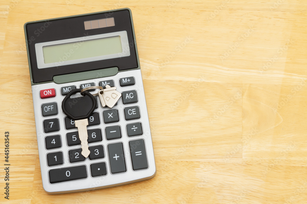 Mortgage calculator with model house on a key chain on wood desk Mortgage calculator with model house on a key chain on wood desk