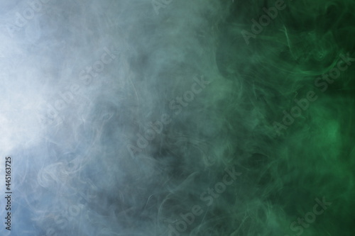 Artificial smoke in grey-green light on black background © Qwenergy