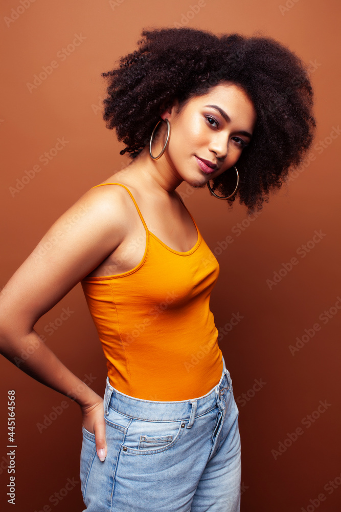 pretty young african american woman with curly hair posing cheerful gesturing on brown background, lifestyle people concept pretty young african american woman with curly hair posing cheerful gesturing on brown background, lifestyle people concept