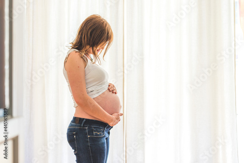 Happy pregnant mother in blue jeans is hugging her tummy, close up Free Download Happy pregnant mother in blue jeans is hugging her tummy, close up - GFXLoad