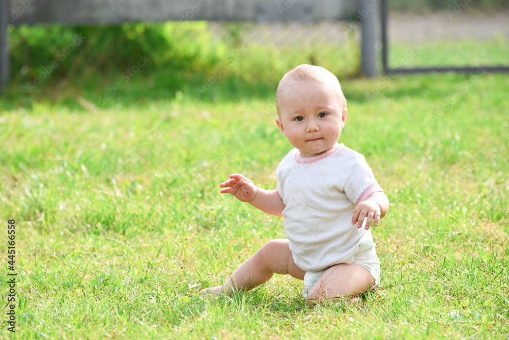 Smiling one year boy sitting in grass outdoors,summer photo Smiling one year boy sitting in grass outdoors,summer photo