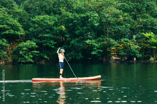 Happy active child on paddle board on water