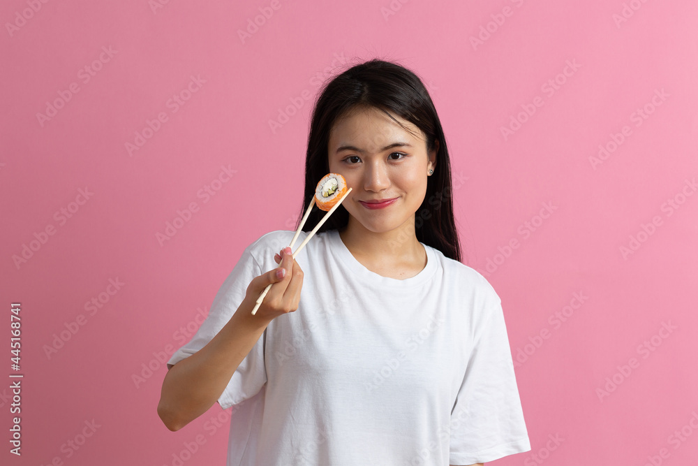 Asian beauty model girl eating Sushi roll, healthy japanese food. Beautiful woman holding chopsticks with Philadelfia roll. Asian beauty model girl eating Sushi roll, healthy japanese food. Beautiful woman holding chopsticks with Philadelfia roll.
