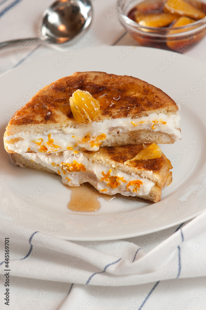 top, front view, close up of, orange, cream, French toast sandwich, stuffed with orange, cream composting drizzled with maple syrup, on round, white plate top, front view, close up of, orange, cream, French toast sandwich, stuffed with orange, cream composting drizzled with maple syrup, on round, white plate