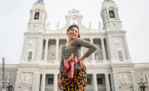 young happy Indonesian woman from Bali having vacation in Europe - attractive and cheerful Balinese tourist girl in traditional outfit touring in the city enjoying holidays trip