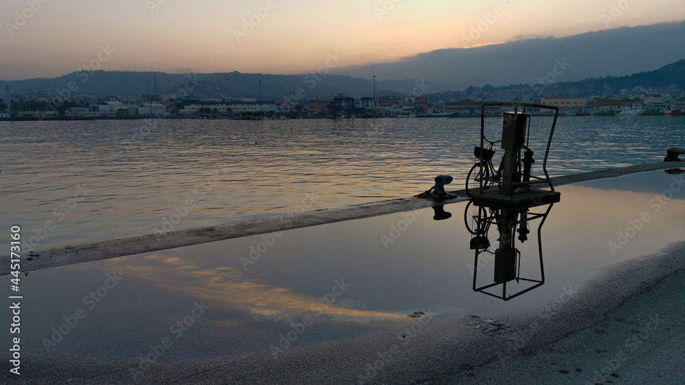 Tramonto sul porto con riflessi sull’acqua che bagna il molo Tramonto sul porto con riflessi sull’acqua che bagna il molo