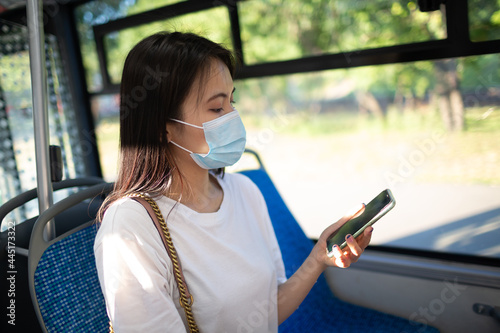 Asian Woman take a ride stand in public transport bus or tram with face mask