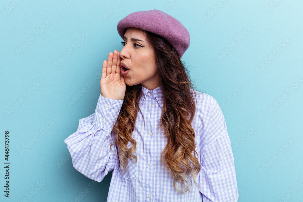 Young mexican woman isolated on blue background is saying a secret hot braking news and looking aside Young mexican woman isolated on blue background is saying a secret hot braking news and looking aside