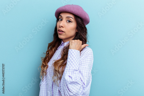 Young mexican woman isolated on blue background points with thumb finger away, laughing and carefree.
