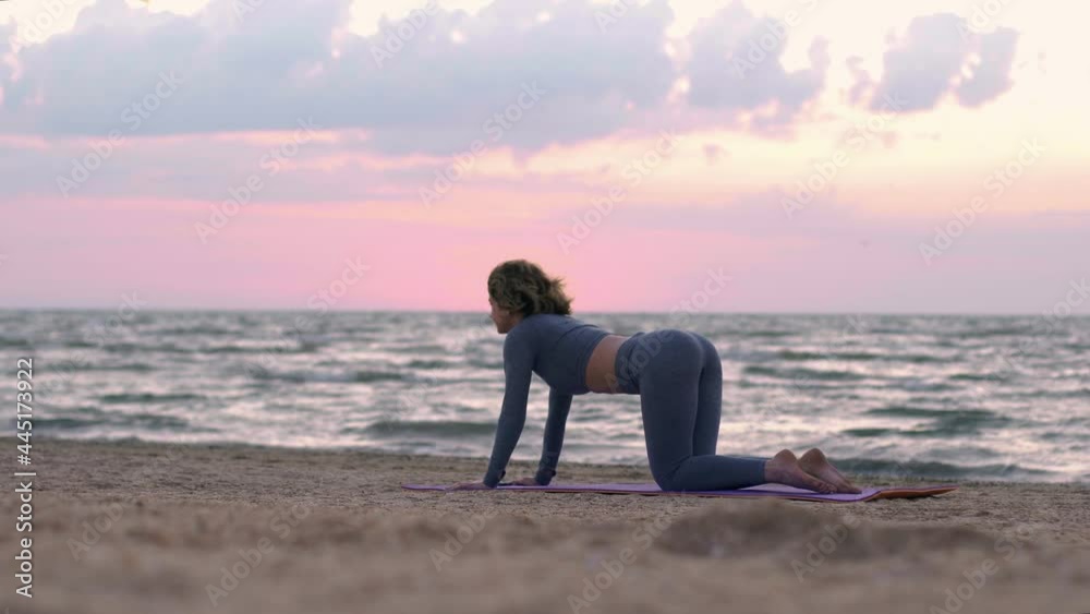 Caucasian woman in sportswear on mat doing workout burning fat calories training strength practicing effort fitness aerobics sport fit. Girl trains muscles and loses weight. Sky and sea horizon Caucasian woman in sportswear on mat doing workout burning fat calories training strength practicing effort fitness aerobics sport fit. Girl trains muscles and loses weight. Sky and sea horizon