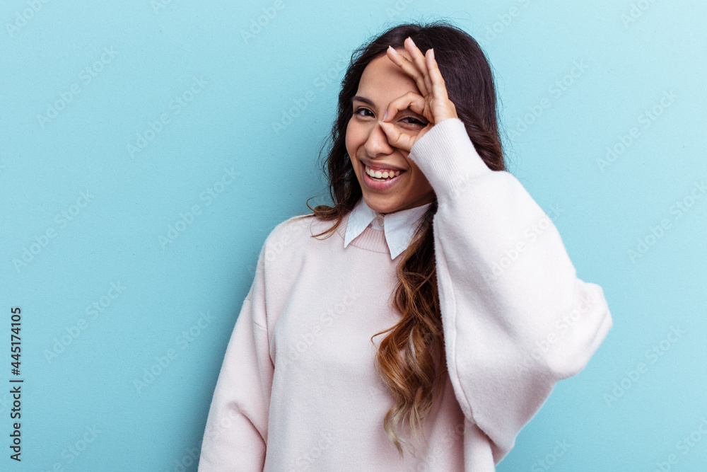 Young mexican woman isolated on blue background excited keeping ok gesture on eye. Young mexican woman isolated on blue background excited keeping ok gesture on eye.