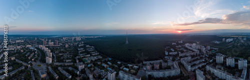 Aerial sunrise panorama wide view Kharkiv city Pavlove Pole district. Multistory buildings near forest with telecommunication tower and scenic early morning dawn sky