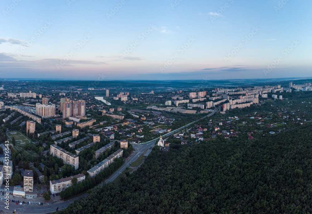 Aerial morning view Kharkiv city Pavlove Pole district Derevianka St. Multistory buildings near forest with scenic blue sky in summer dawn light Aerial morning view Kharkiv city Pavlove Pole district Derevianka St. Multistory buildings near forest with scenic blue sky in summer dawn light