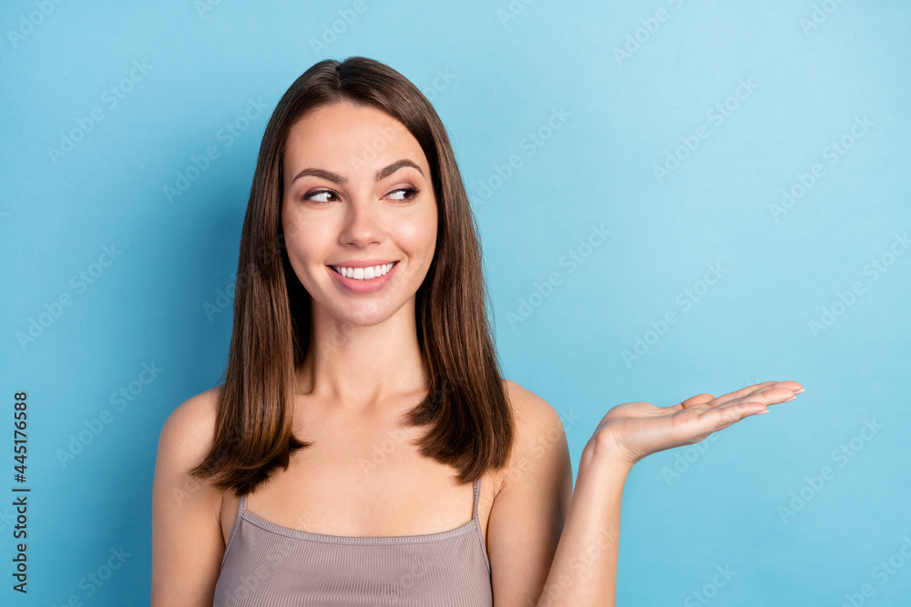 Photo portrait pretty woman curious keeping empty space on hand isolated pastel blue color background Photo portrait pretty woman curious keeping empty space on hand isolated pastel blue color background
