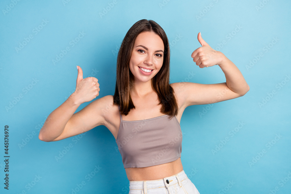 Photo of shiny charming young woman dressed gray top smiling showing thumbs up isolated blue color background Photo of shiny charming young woman dressed gray top smiling showing thumbs up isolated blue color background