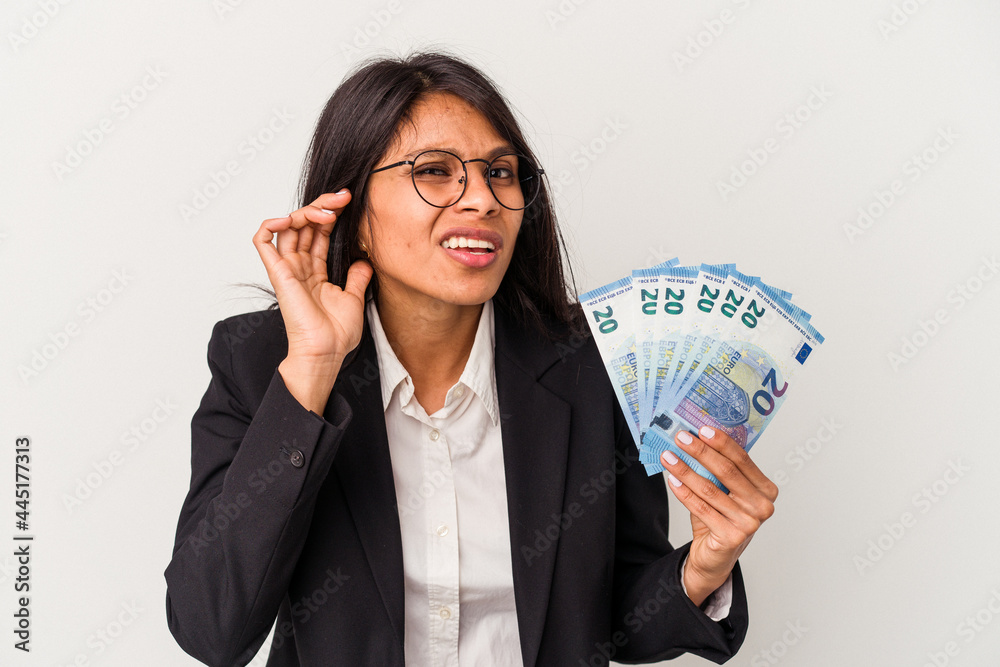 Young business latin woman holding bills isolated on white background trying to listening a gossip. Young business latin woman holding bills isolated on white background trying to listening a gossip.