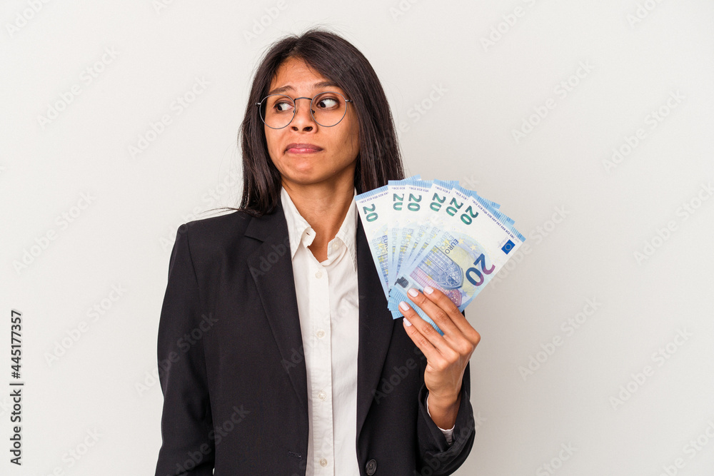 Young business latin woman holding bills isolated on white background confused, feels doubtful and unsure. Young business latin woman holding bills isolated on white background confused, feels doubtful and unsure.