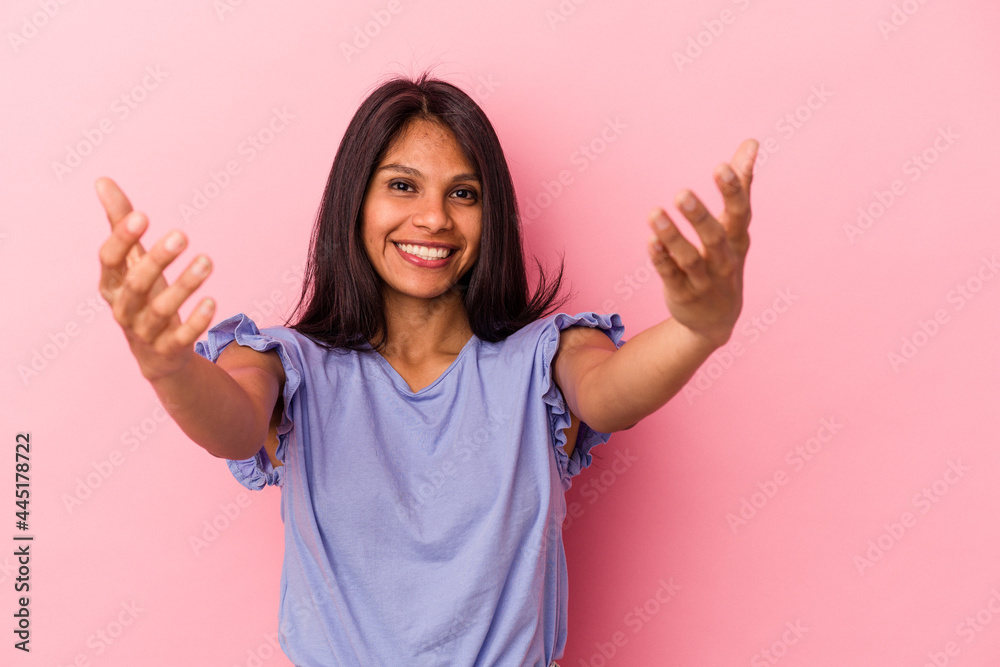 Young latin woman isolated on pink background showing a welcome expression. Young latin woman isolated on pink background showing a welcome expression.