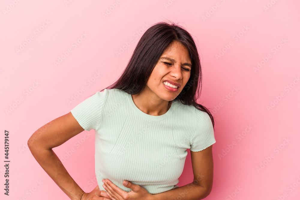 Young latin woman isolated on pink background having a liver pain, stomach ache. Young latin woman isolated on pink background having a liver pain, stomach ache.