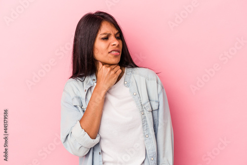 Young latin woman isolated on pink background touching back of head, thinking and making a choice.