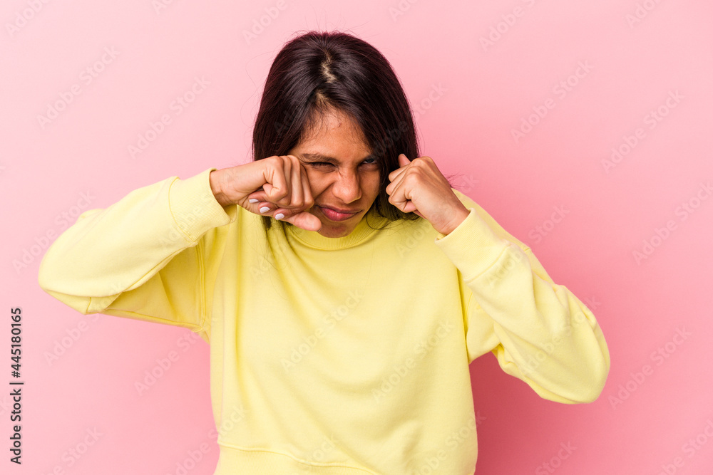 Young latin woman isolated on pink background throwing a punch, anger, fighting due to an argument, boxing.