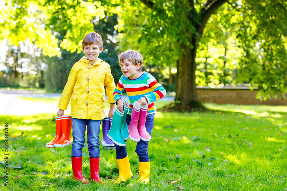 Fototapeta premium Two little kids boys, cute siblings with lots of colorful rain boots. Children in different rubber boots and jackets. Footwear for rainy fall. Healthy twins and best friends having fun outdoors