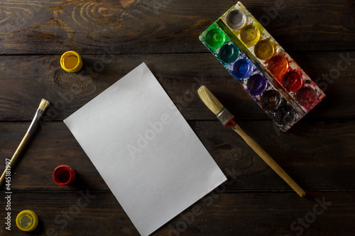 a blank sheet of paper on the table with a brush and paints
