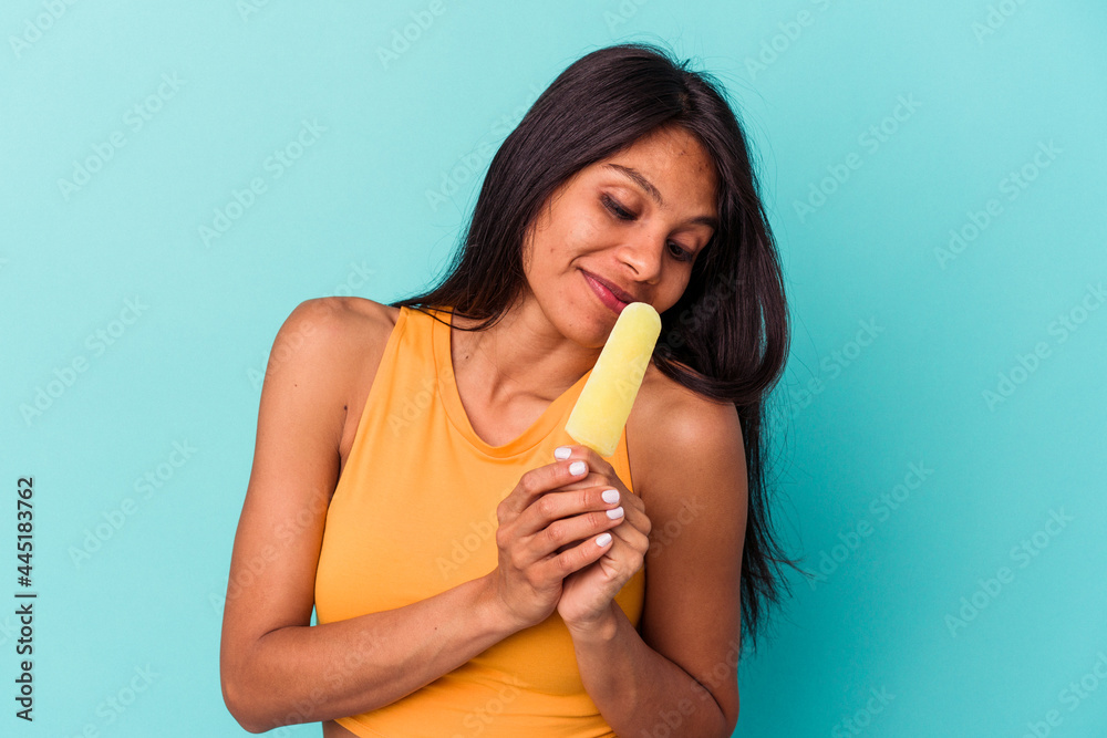 Young latin woman holding ice cream isolated on blue background Young latin woman holding ice cream isolated on blue background