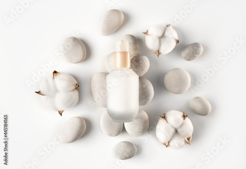 Beautiful spa composition of natural cosmetics mockup bottle with cotton flowers and sea pebbles on white background. Top view. Flat lay style. Copy space.
