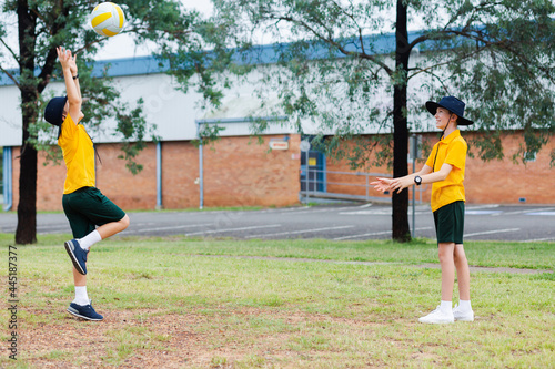 Two Aussie school boys throwing a ball together outside