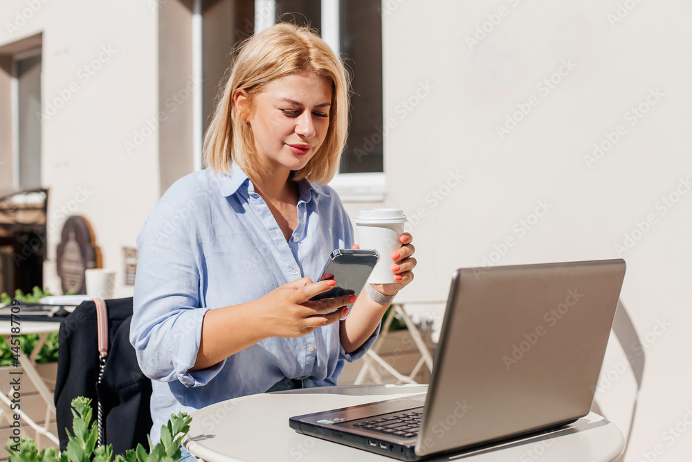 Beautiful young woman in a blue shirt working on a notebook in a cafe and drink coffee. Remote work concept. Education online Beautiful young woman in a blue shirt working on a notebook in a cafe and drink coffee. Remote work concept. Education online
