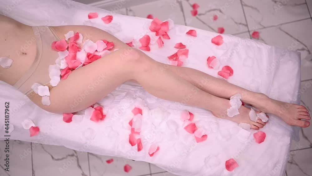 Laser epilation and cosmetology in beauty salon. Hair removal procedure. Laser epilation, cosmetology, spa, and hair removal concept. falling rose petals on beautiful female slender legs Laser epilation and cosmetology in beauty salon. Hair removal procedure. Laser epilation, cosmetology, spa, and hair removal concept. falling rose petals on beautiful female slender legs
