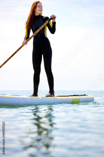 Photography Fit female athlete surfing in sea, redhead caucasian Surfer woman performing outdoor inside ocean, subsurfing alone