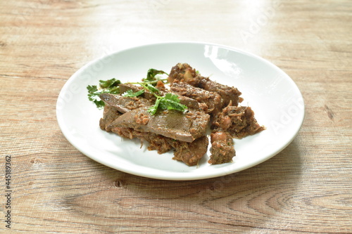 fried slice pork meat and liver with garlic couple pepper topping parsley on plate