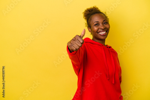 Young african american woman isolated on yellow background smiling and raising thumb up © Asier